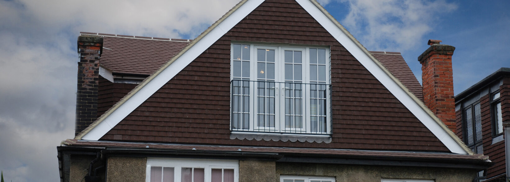 Pitched dormer loft conversion exterior with tiled roof, front glazing and balcony railings for a Plumstead SE18 home