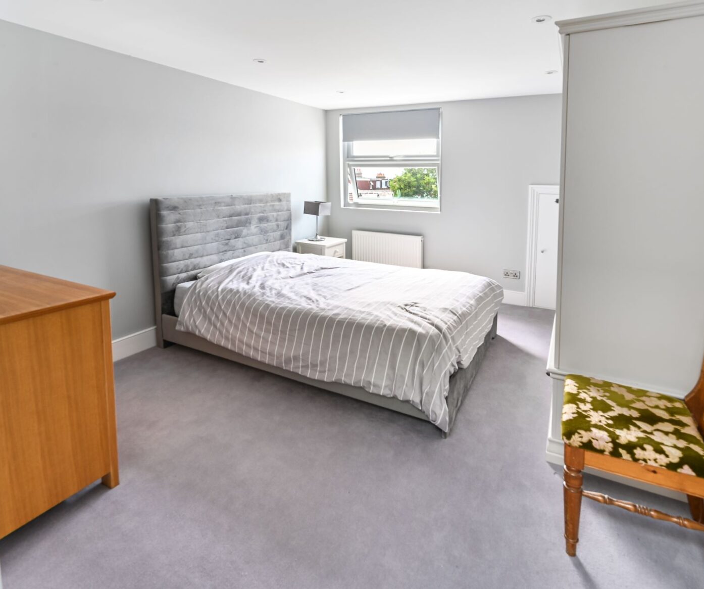 Modern dormer loft conversion master bedroom in Barnet with grey velvet headboard and large window