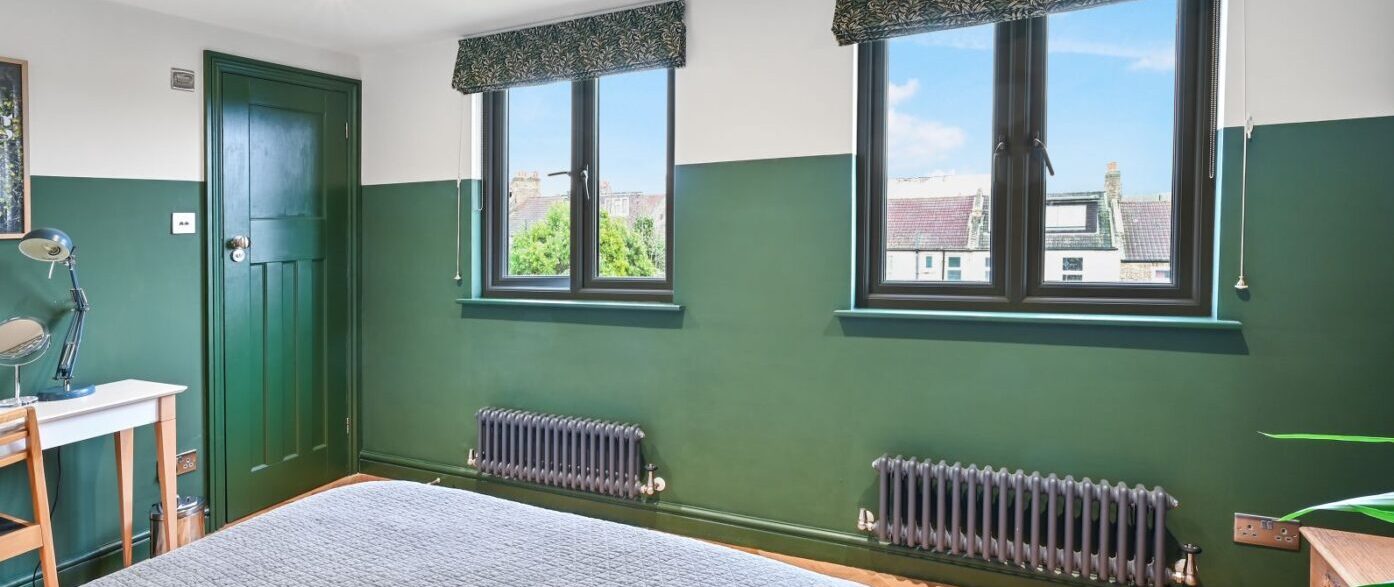 Green loft bedroom in Stanmore HA7 with twin windows, parquet flooring and period style radiators