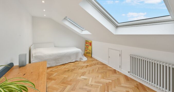 Velux loft room in Stanmore HA7 with herringbone flooring, white walls and a simple day bed