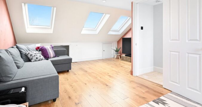 Bright loft living room with three rooflights, pale walls and oak flooring.