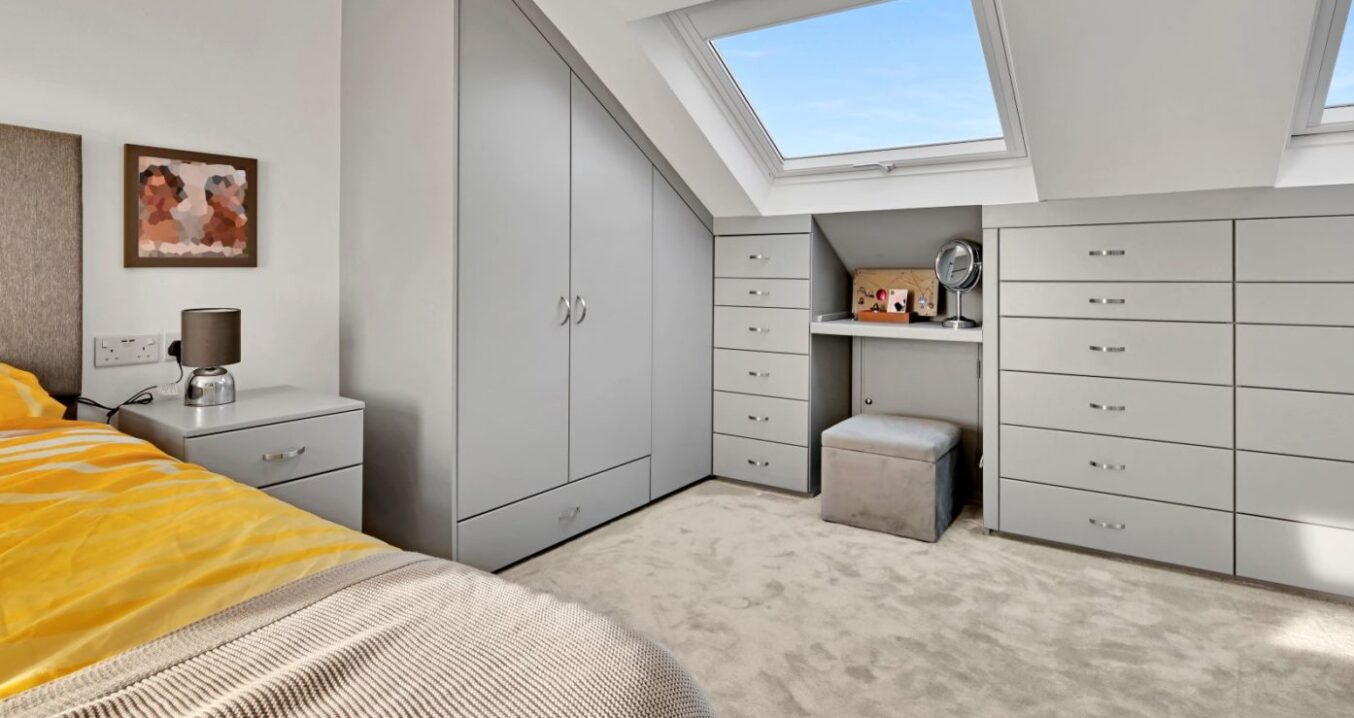 Loft conversion bedroom with fitted wardrobes, drawers, roof window and dressing area for an Epping CM16 home.