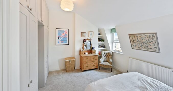 Loft conversion bedroom with fitted wardrobes, soft carpet and sloping ceiling storage for an Epping CM16 property.