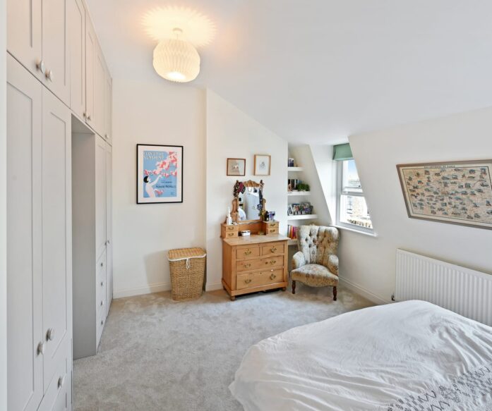 Loft conversion bedroom with fitted wardrobes, soft carpet and sloping ceiling storage for an Epping CM16 property.
