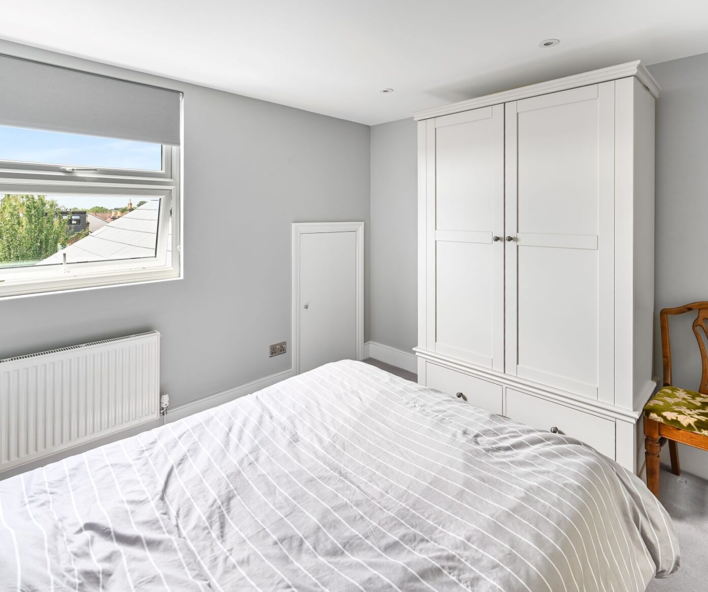 Loft conversion bedroom with rear window, white wardrobe and grey walls for an Epping CM16 property.