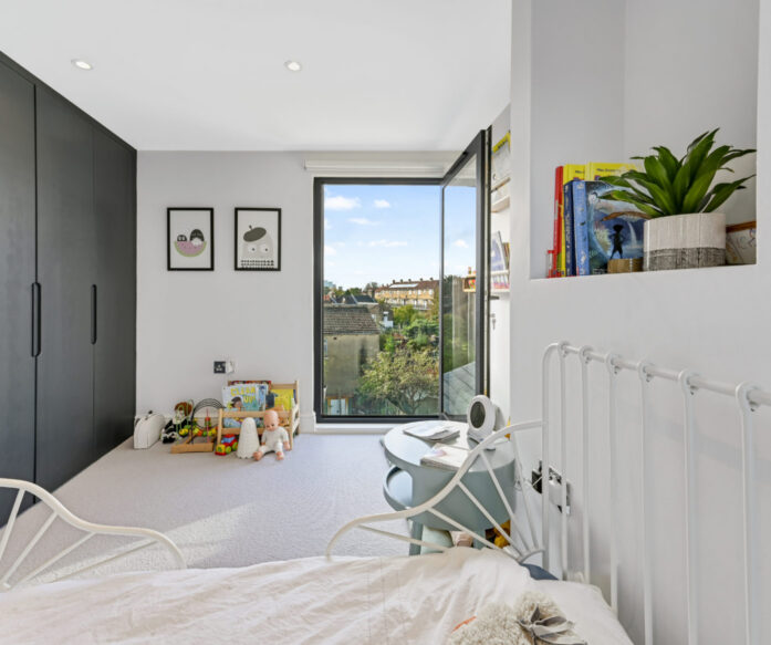 Loft conversion children’s bedroom with fitted storage, open glazed door and bright natural light for an Epping CM16 home.