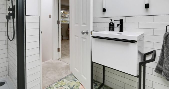 Loft conversion en suite shower room with white tiles, black fittings and patterned floor for an Epping CM16 home.