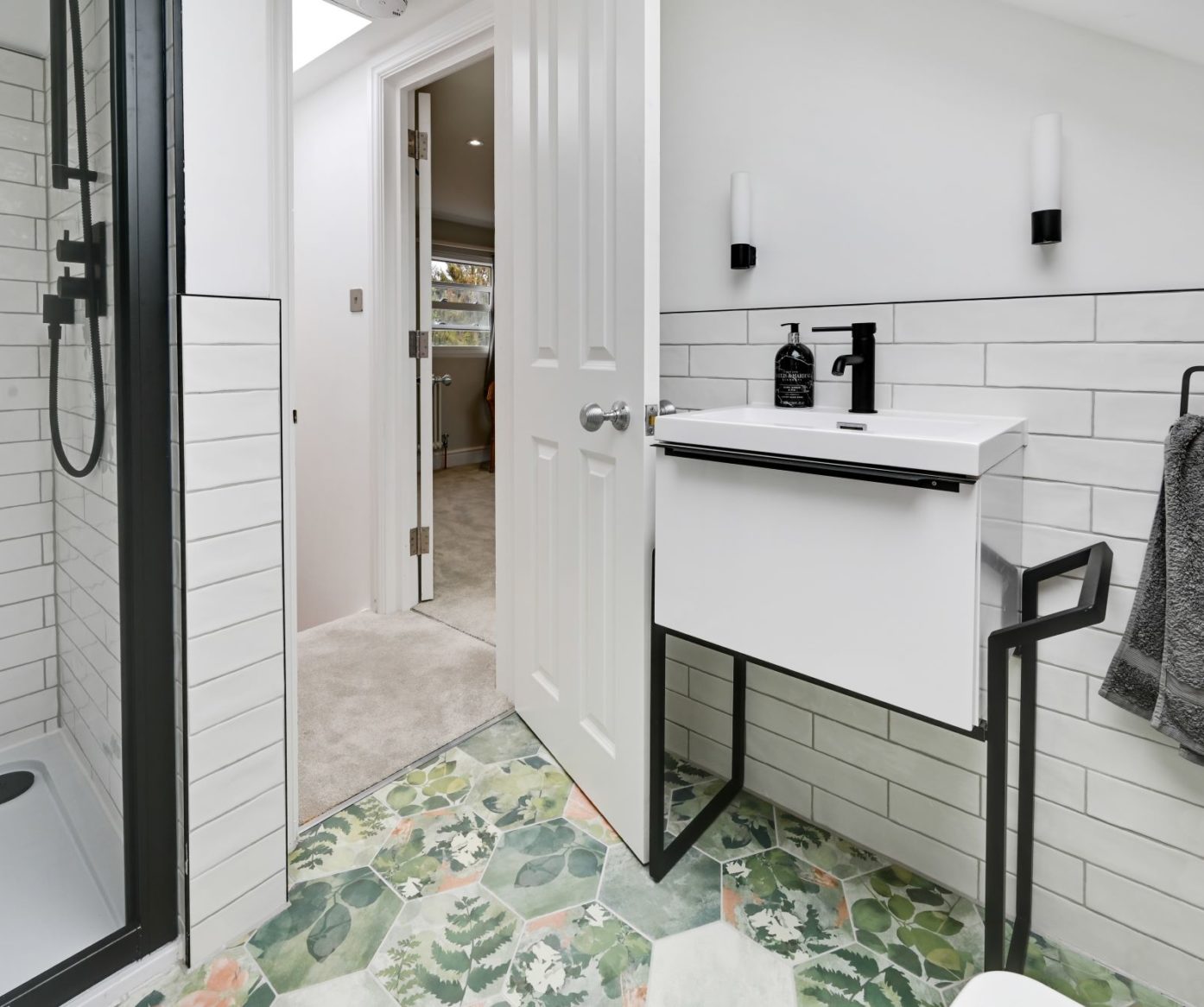 Loft conversion en suite shower room with white tiles, black fittings and patterned floor for an Epping CM16 home.