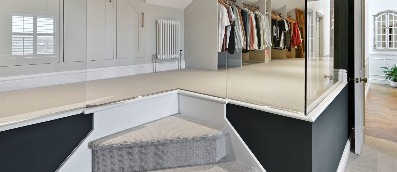 Loft dressing area with fitted wardrobes, carpeted floor and hallway access, supporting Palmers Green N13 loft design.