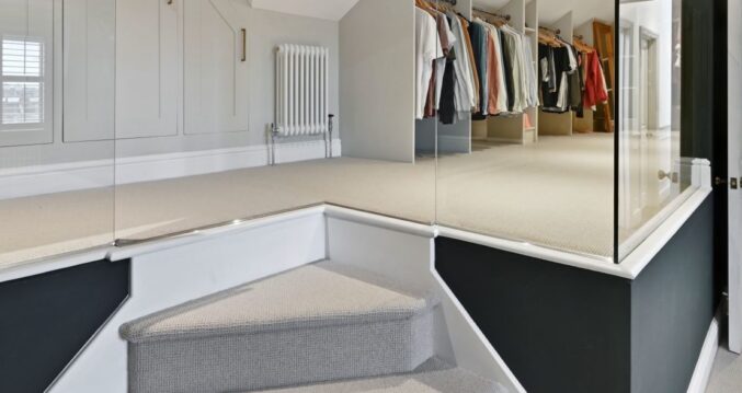 Loft dressing area with fitted wardrobes, carpeted floor and hallway access, supporting Palmers Green N13 loft design.