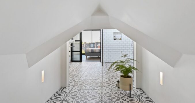 Loft hallway with patterned tiled floor leading towards a bedroom and bathroom.