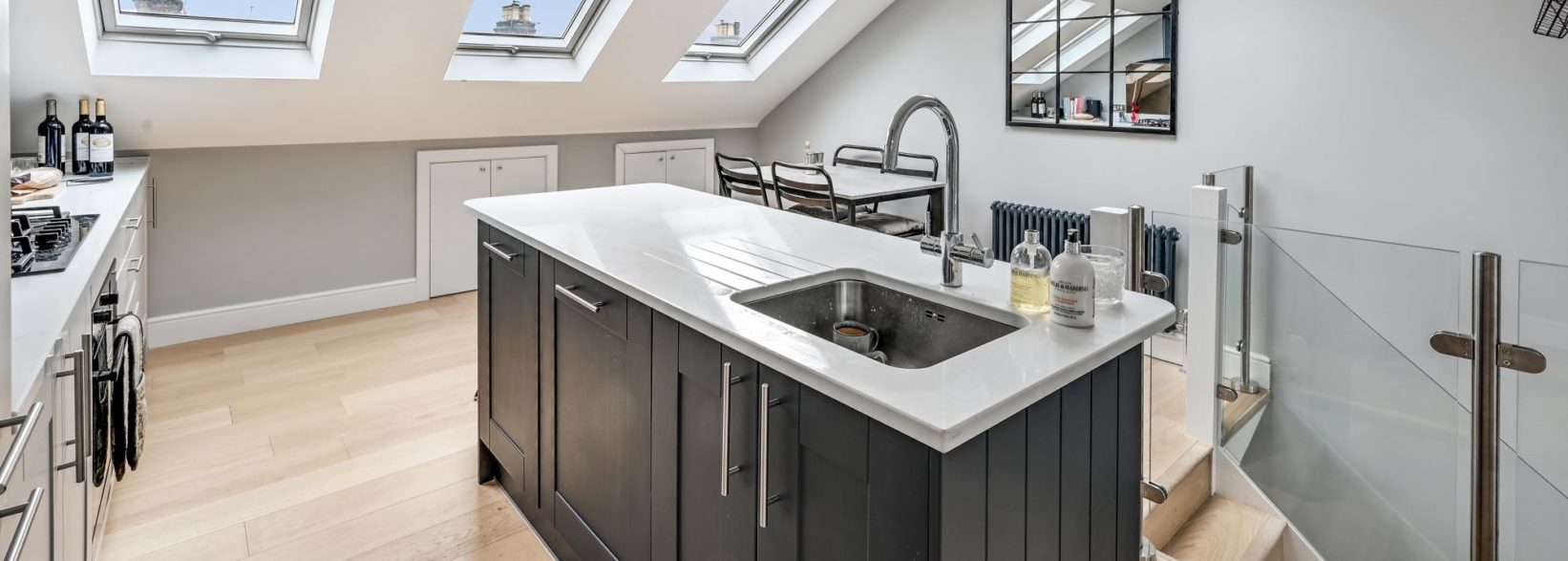 Loft kitchen space with island unit, rooflights and dining area, supporting the Palmers Green N13 Our Work page.