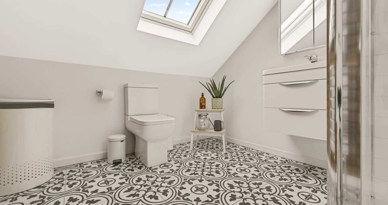 Compact loft shower room with patterned floor tiles, rooflight and sloping ceiling in Palmers Green N13.
