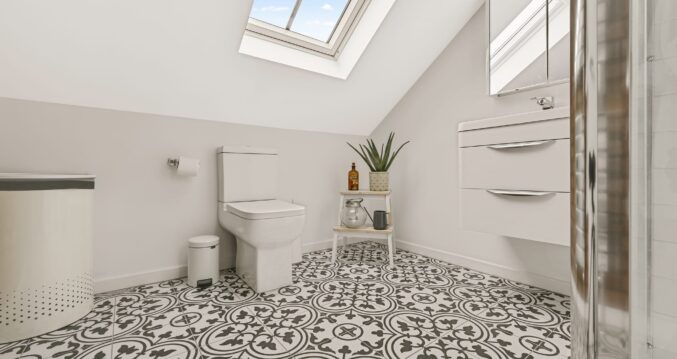 Compact loft shower room with patterned floor tiles, rooflight and sloping ceiling in Palmers Green N13.