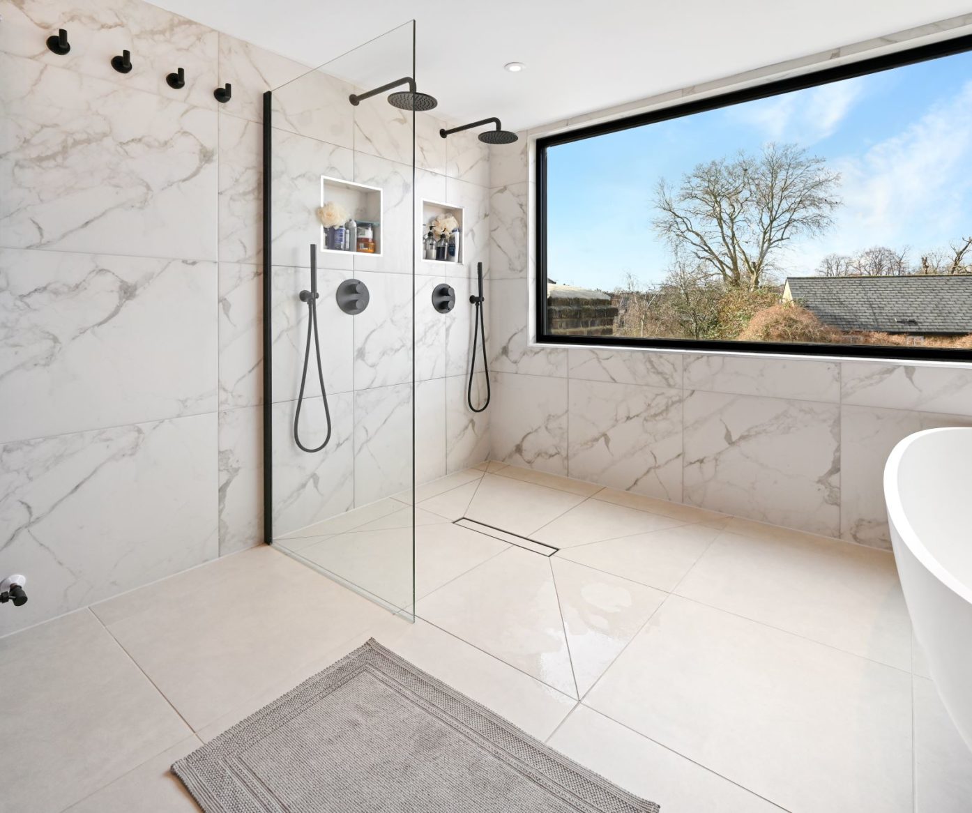 Luxury loft bathroom with large walk-in shower, marble effect wall tiles and picture window in Palmers Green N13.