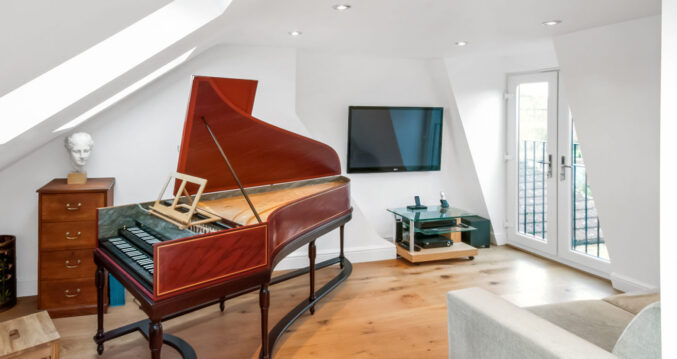 Bright mansard loft music room with wooden flooring, grand piano and French doors, used as inspiration for a Palmers Green loft conversion page.