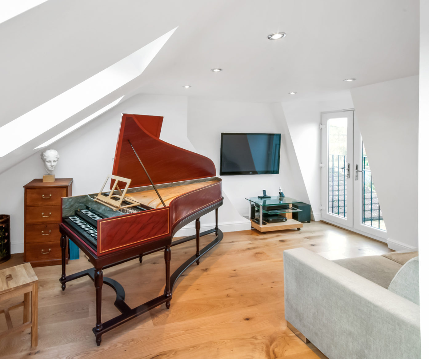Bright mansard loft music room with wooden flooring, grand piano and French doors, used as inspiration for a Palmers Green loft conversion page.