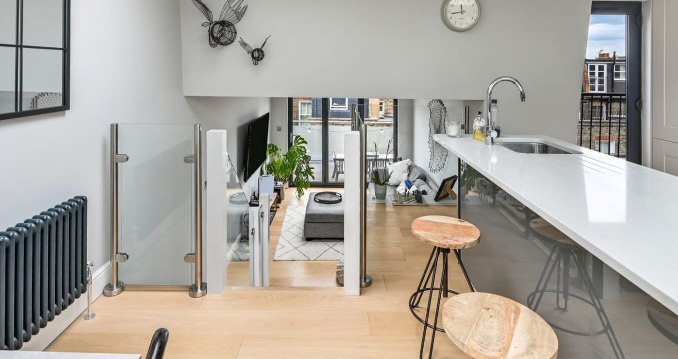 Open plan loft living space with kitchen area, rooflight and glass balustrade in Palmers Green N13.