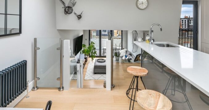Open plan loft living space with kitchen area, rooflight and glass balustrade in Palmers Green N13.