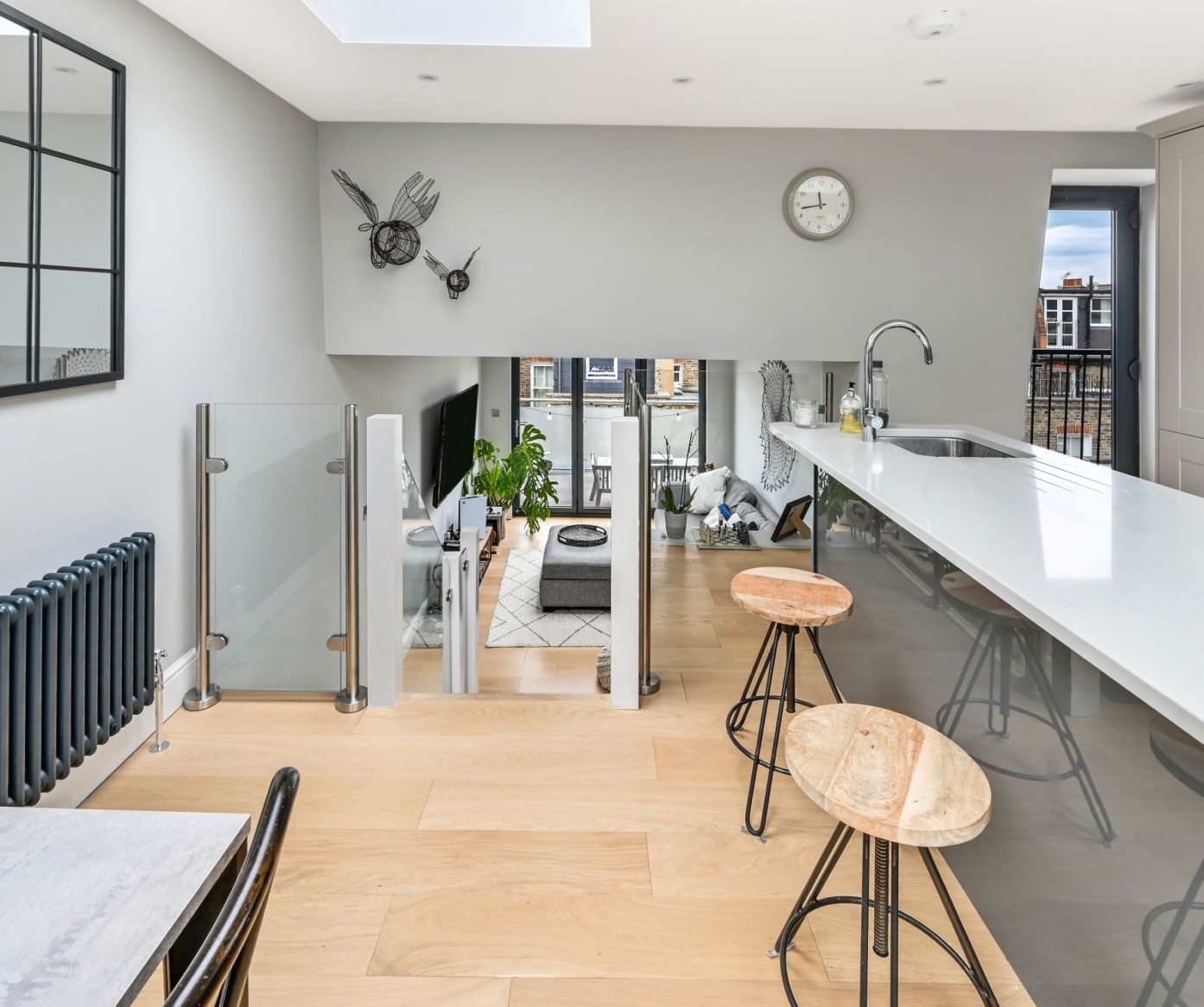 Open plan loft living space with kitchen area, rooflight and glass balustrade in Palmers Green N13.
