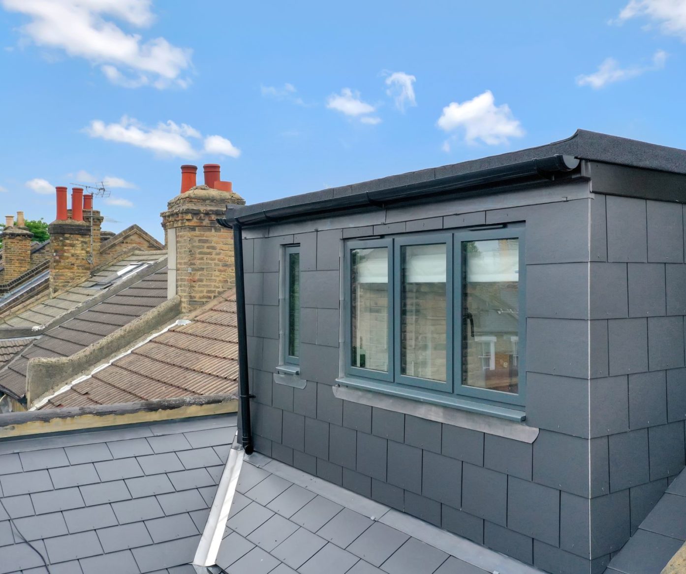 Rear dormer loft exterior with dark cladding, flat roof and modern windows in Palmers Green N13.