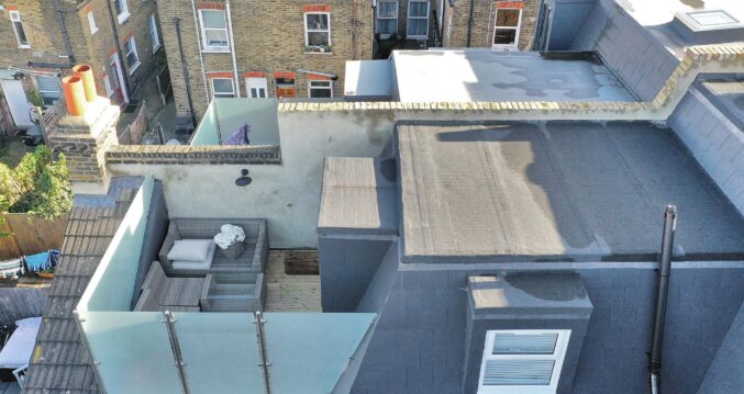 Loft roof terrace with glass balustrade, seating area and French doors in Palmers Green N13.