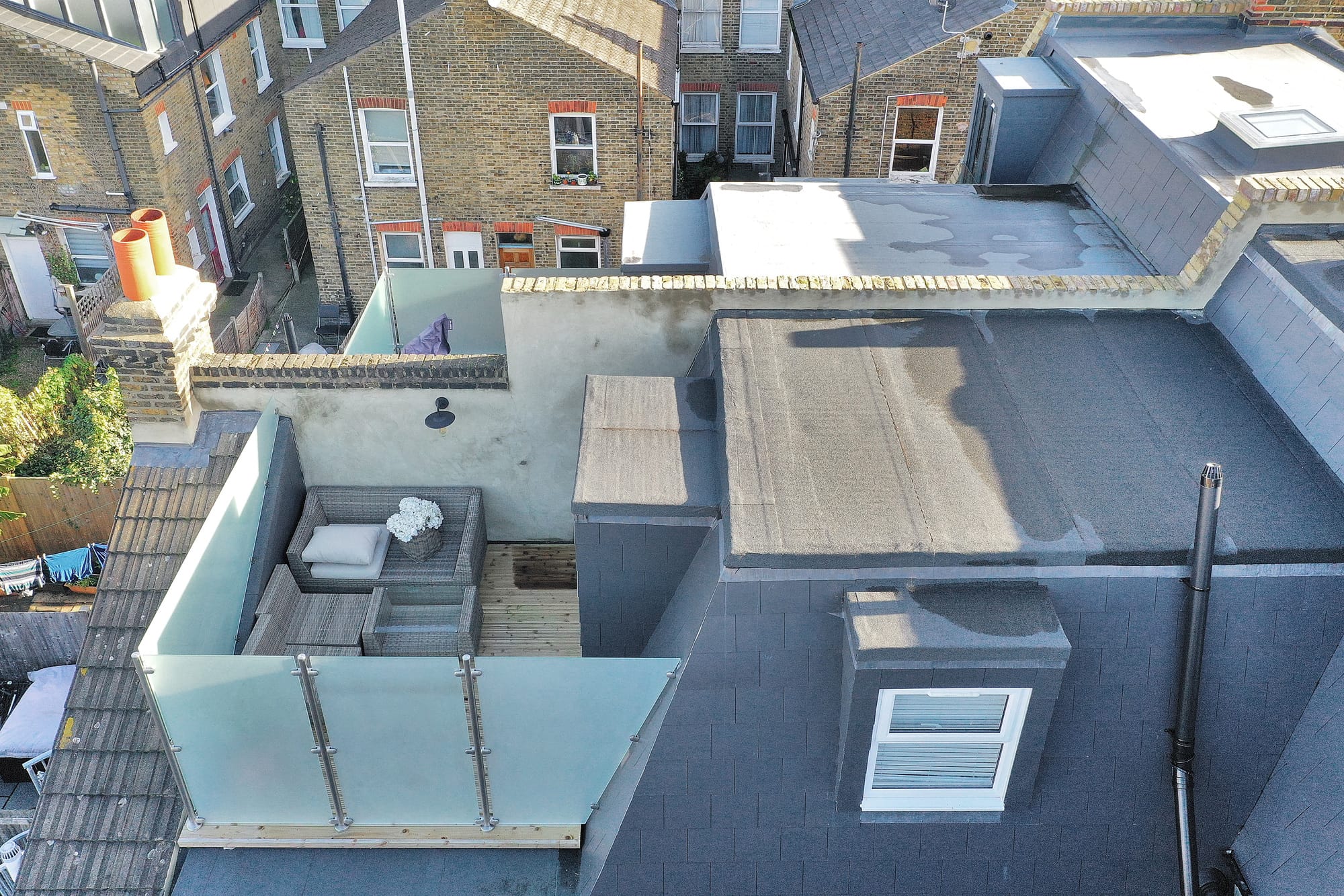 Loft roof terrace with glass balustrade, seating area and French doors in Palmers Green N13.