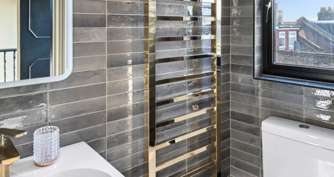 Grey tiled loft bathroom with basin, heated towel rail, modern fittings and window, supporting Crystal Palace loft conversion content.