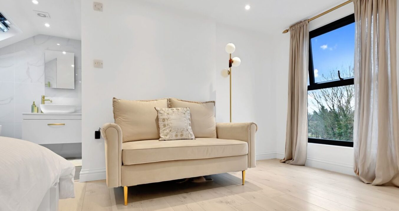 Large loft bedroom with sofa, wide window, pale flooring and en-suite area, supporting Crystal Palace main bedroom loft ideas.