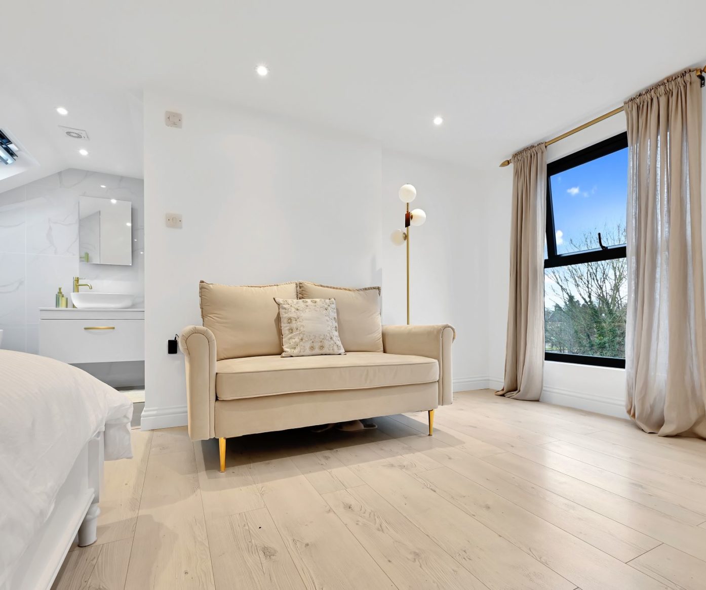 Large loft bedroom with sofa, wide window, pale flooring and en-suite area, supporting Crystal Palace main bedroom loft ideas.
