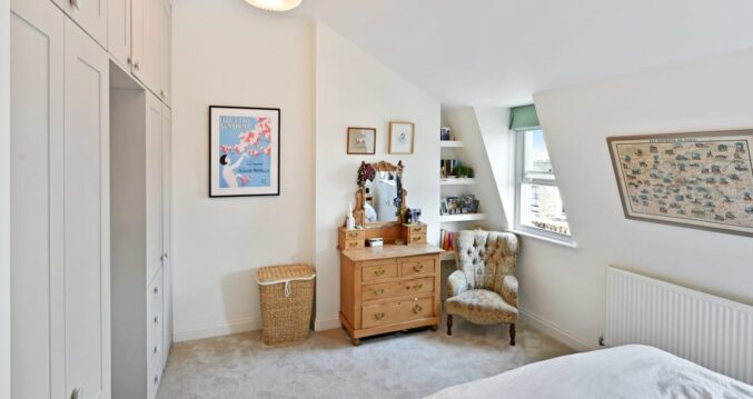 Loft bedroom with built-in wardrobes, bed, chair, window and neutral finish, supporting Crystal Palace loft conversion bedroom content.