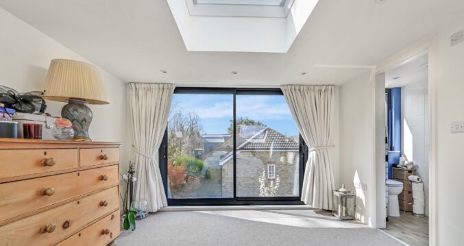 Bright loft bedroom with large French doors, roof window and en suite access in an Edgware HA8 loft conversion.