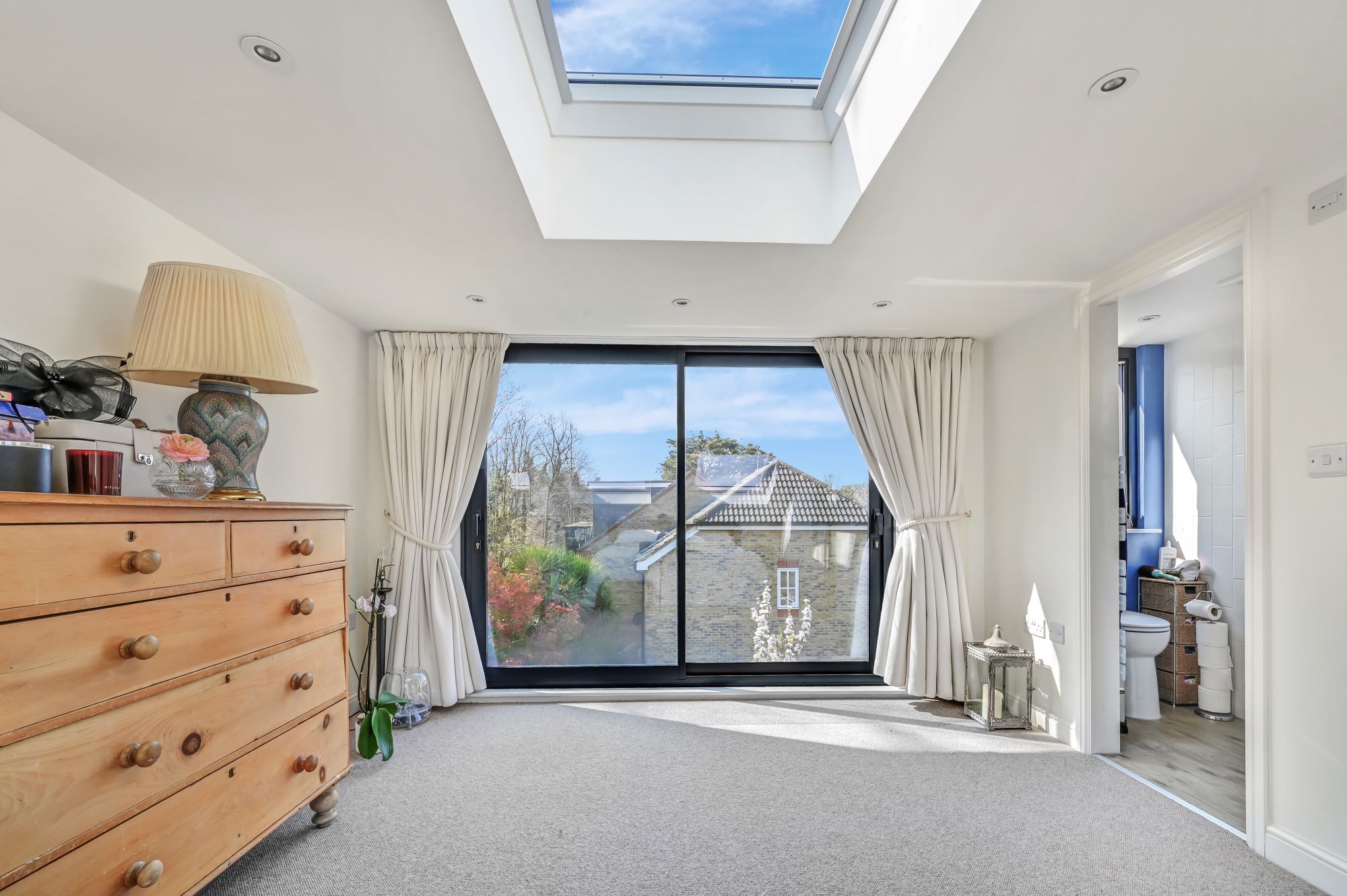 Bright loft bedroom with large French doors, roof window and en suite access in an Edgware HA8 loft conversion.