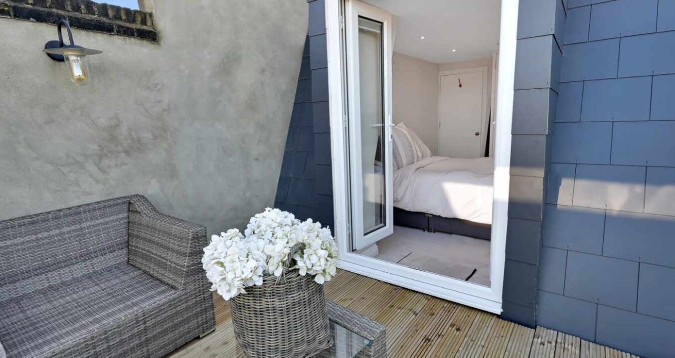 Mansard loft terrace with decked outdoor space, grey cladding and open bedroom doors, supporting Crystal Palace loft conversion ideas.