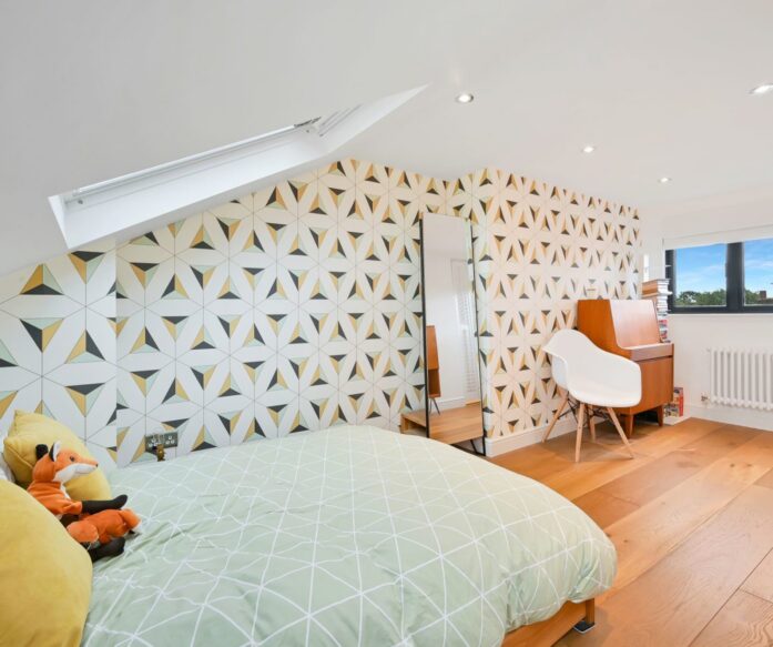 Children’s loft bedroom with patterned wall, bed, desk, rooflight and timber flooring, supporting SE20 family loft conversion ideas.