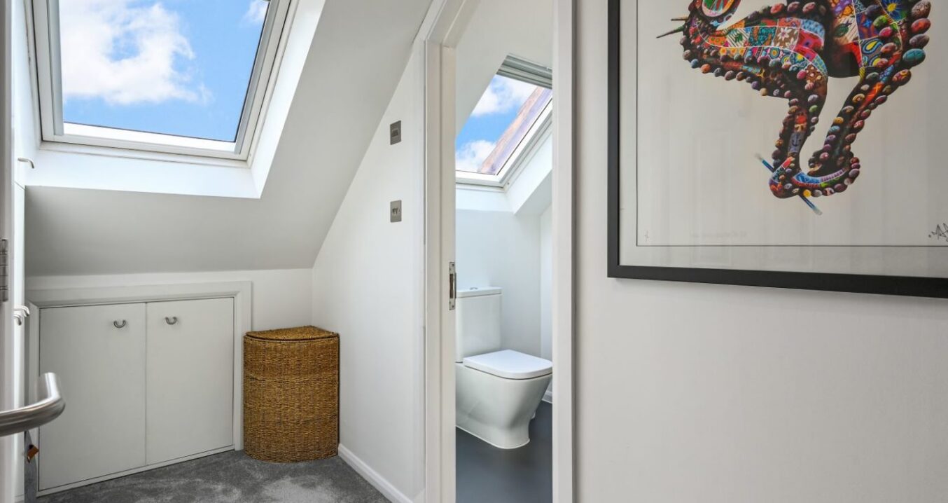 Loft bedroom landing with rooflight, storage, grey carpet and shower room doorway, supporting SE20 loft conversion layout content.