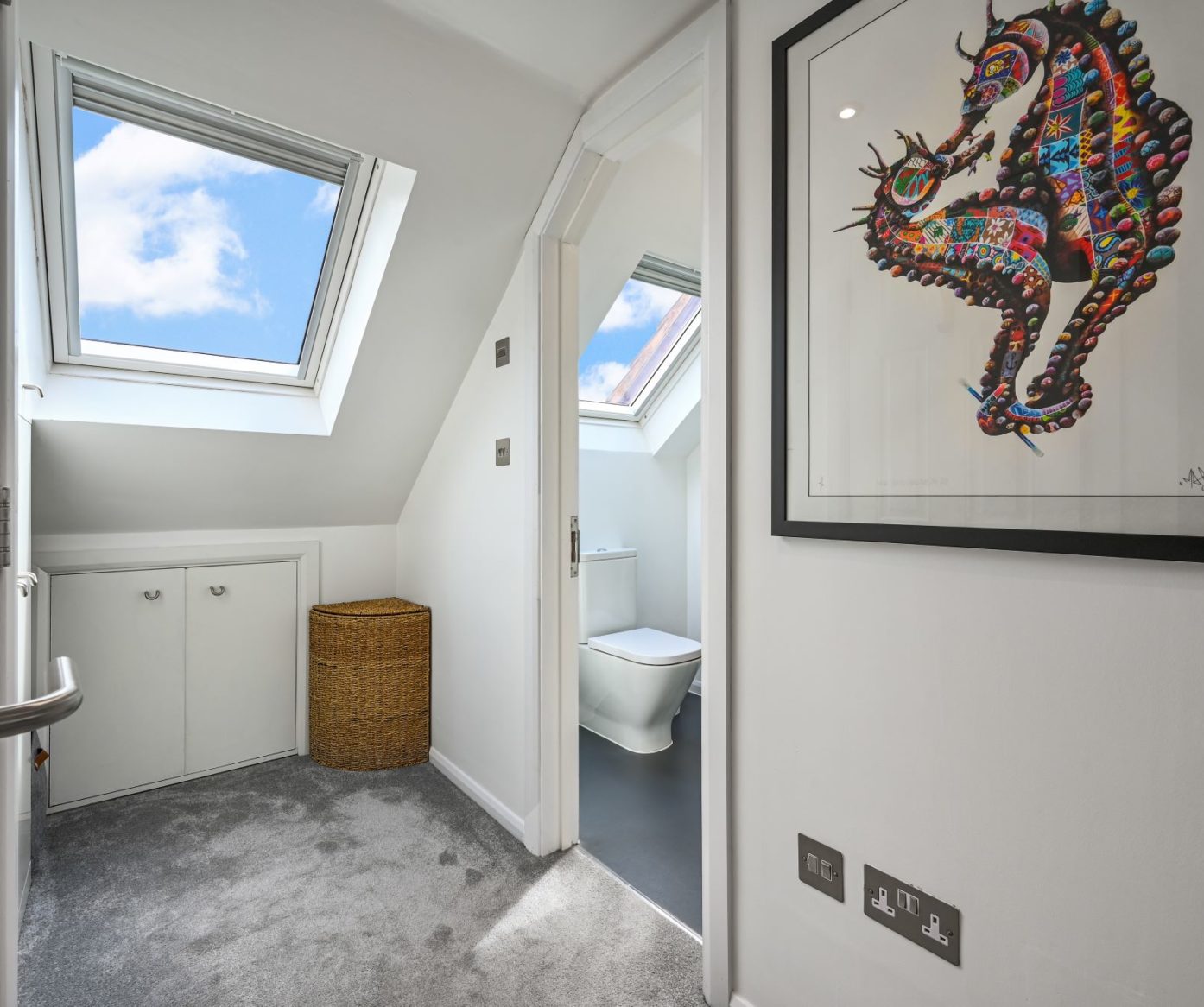 Loft bedroom landing with rooflight, storage, grey carpet and shower room doorway, supporting SE20 loft conversion layout content.
