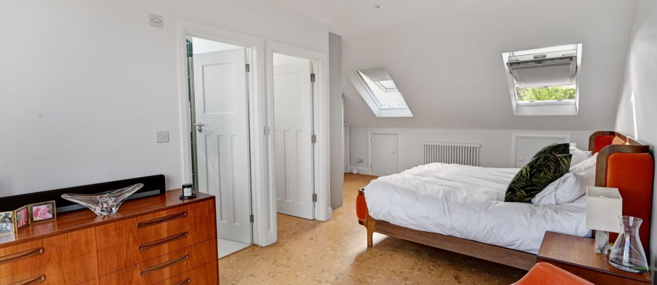 Spacious loft bedroom with rooflights, bed, white doors and neutral walls, supporting Crystal Palace loft conversion planning.