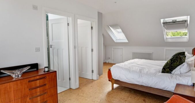Spacious loft bedroom with rooflights, bed, white doors and neutral walls, supporting Crystal Palace loft conversion planning.