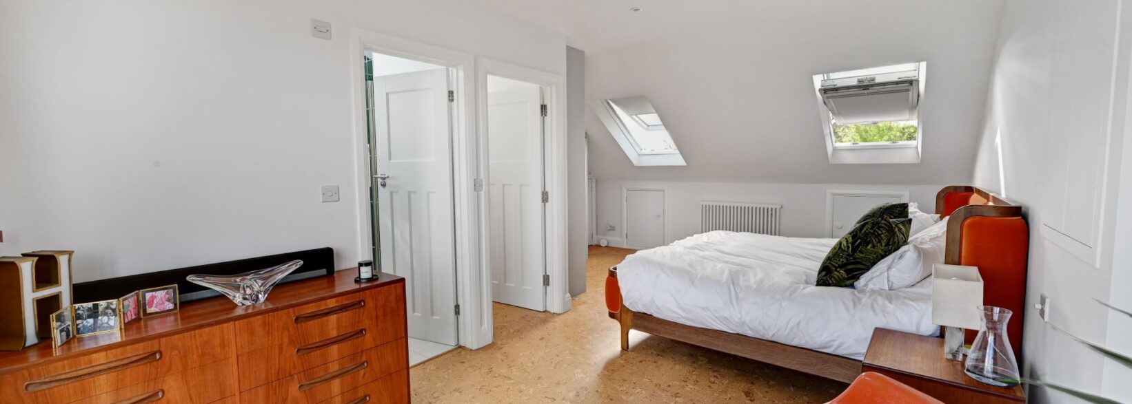 Spacious loft bedroom with rooflights, bed, white doors and neutral walls, supporting Crystal Palace loft conversion planning.