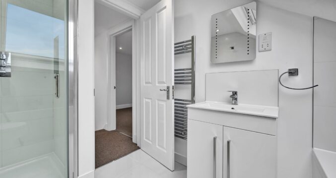 White loft shower room with walk-in shower, vanity unit and tiled walls in an Edgware HA8 loft conversion.