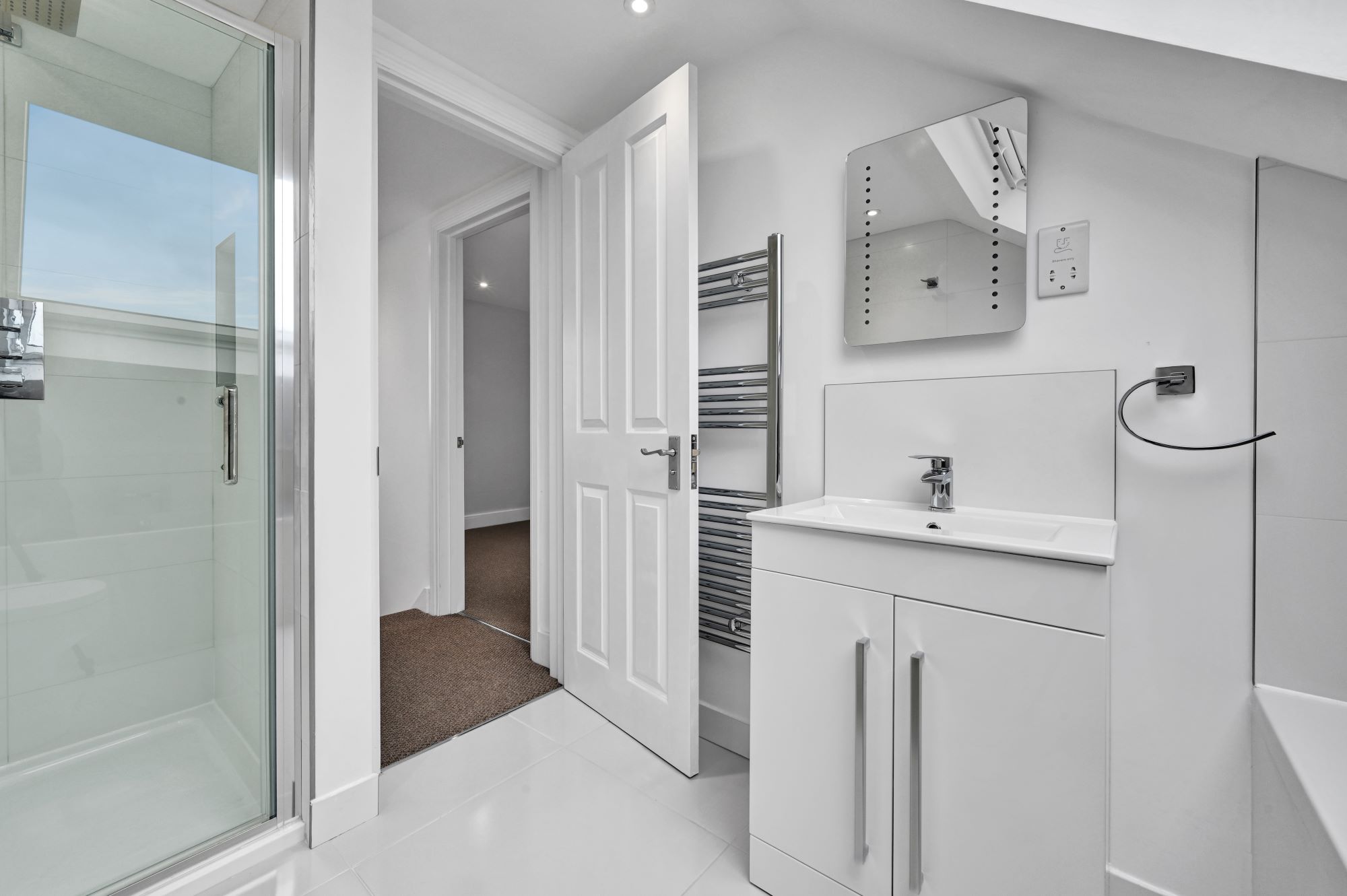 White loft shower room with walk-in shower, vanity unit and tiled walls in an Edgware HA8 loft conversion.