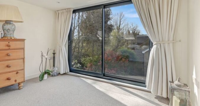 Dormer loft bedroom with wide aluminium sliding doors overlooking the garden in a Winchmore Hill N21 conversion