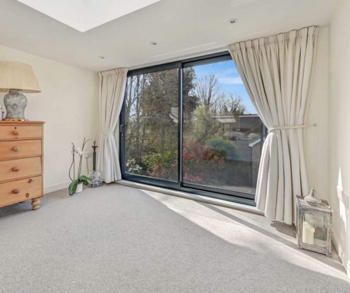 Dormer loft bedroom with wide aluminium sliding doors overlooking the garden in a Winchmore Hill N21 conversion