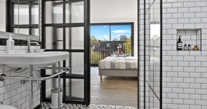 Industrial-style loft shower room with black-framed screens and white metro tiles in a Winchmore Hill N21 conversion