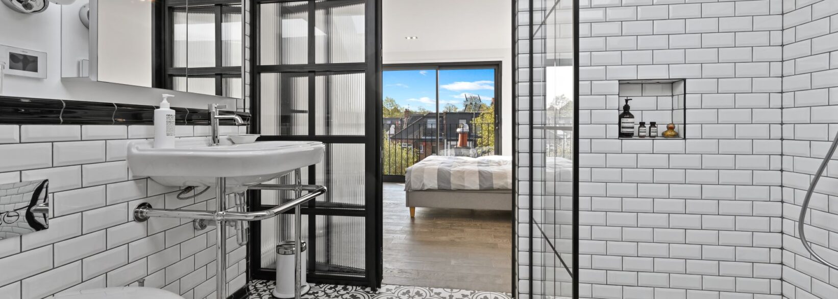 Industrial-style loft shower room with black-framed screens and white metro tiles in a Winchmore Hill N21 conversion