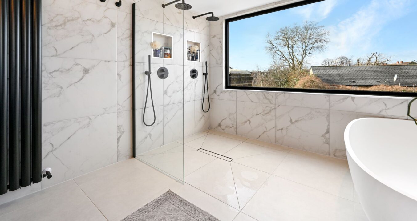 Luxury loft bathroom with walk in double shower, marble effect tiling, freestanding bath and wide picture window for the Wood Green N22 page.
