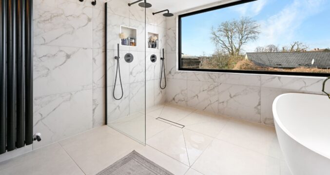 Luxury loft bathroom with walk in double shower, marble effect tiling, freestanding bath and wide picture window for the Wood Green N22 page.