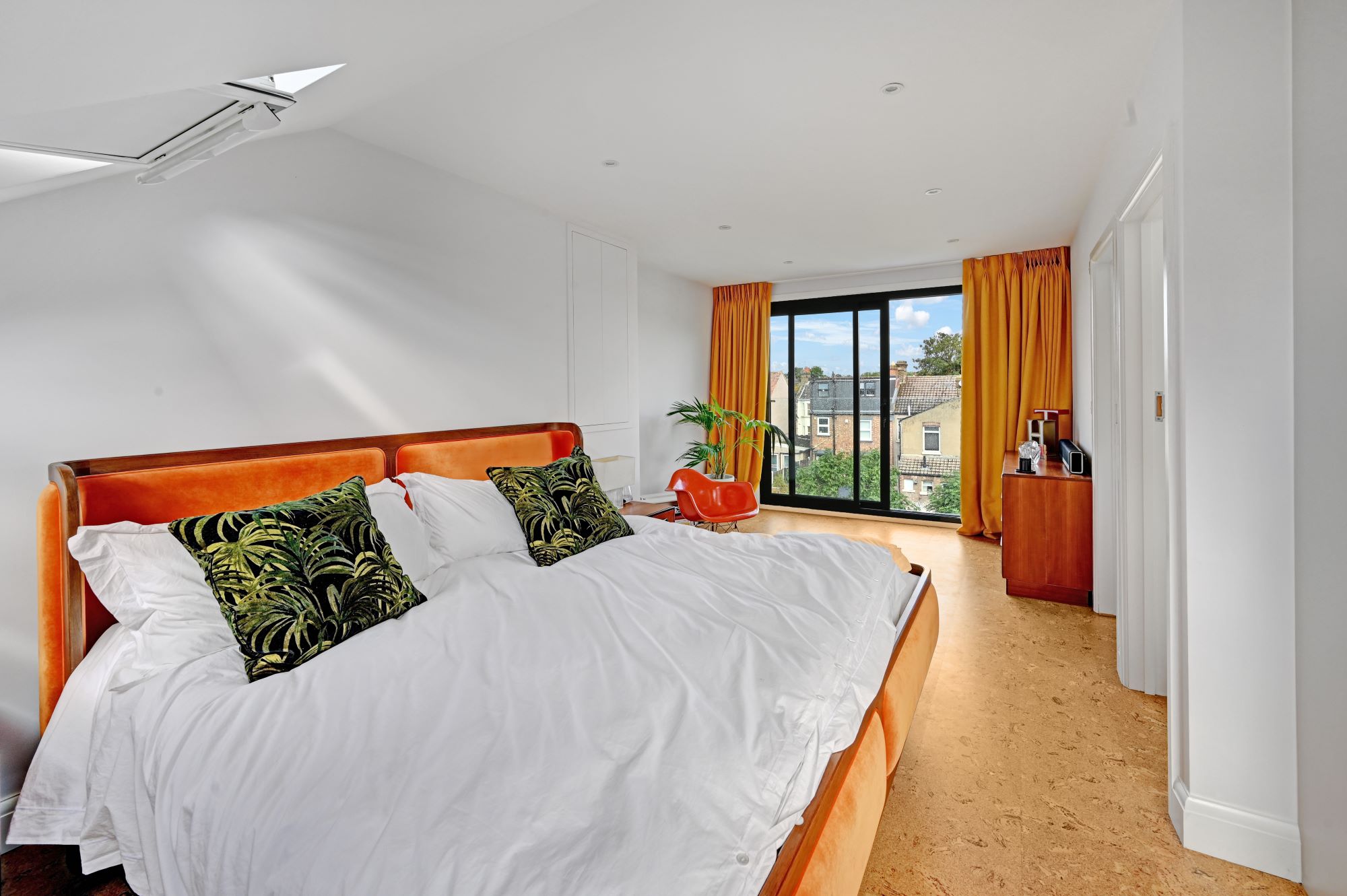 Spacious loft bedroom with full height black framed glazing, timber flooring and contemporary finishes for the Wood Green N22 loft conversion page.