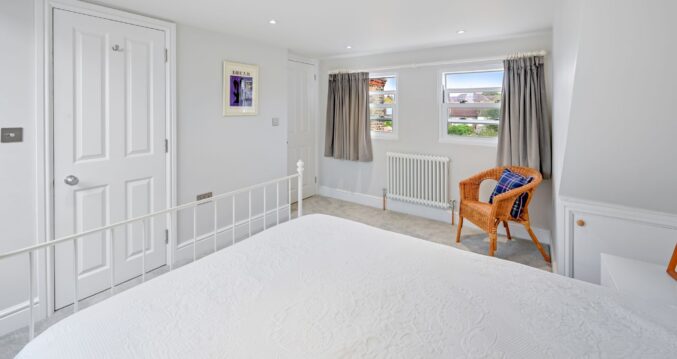 Finished loft bedroom with twin rear windows, recessed lighting, fitted storage and neutral finishes for the Wood Green N22 loft conversion page.